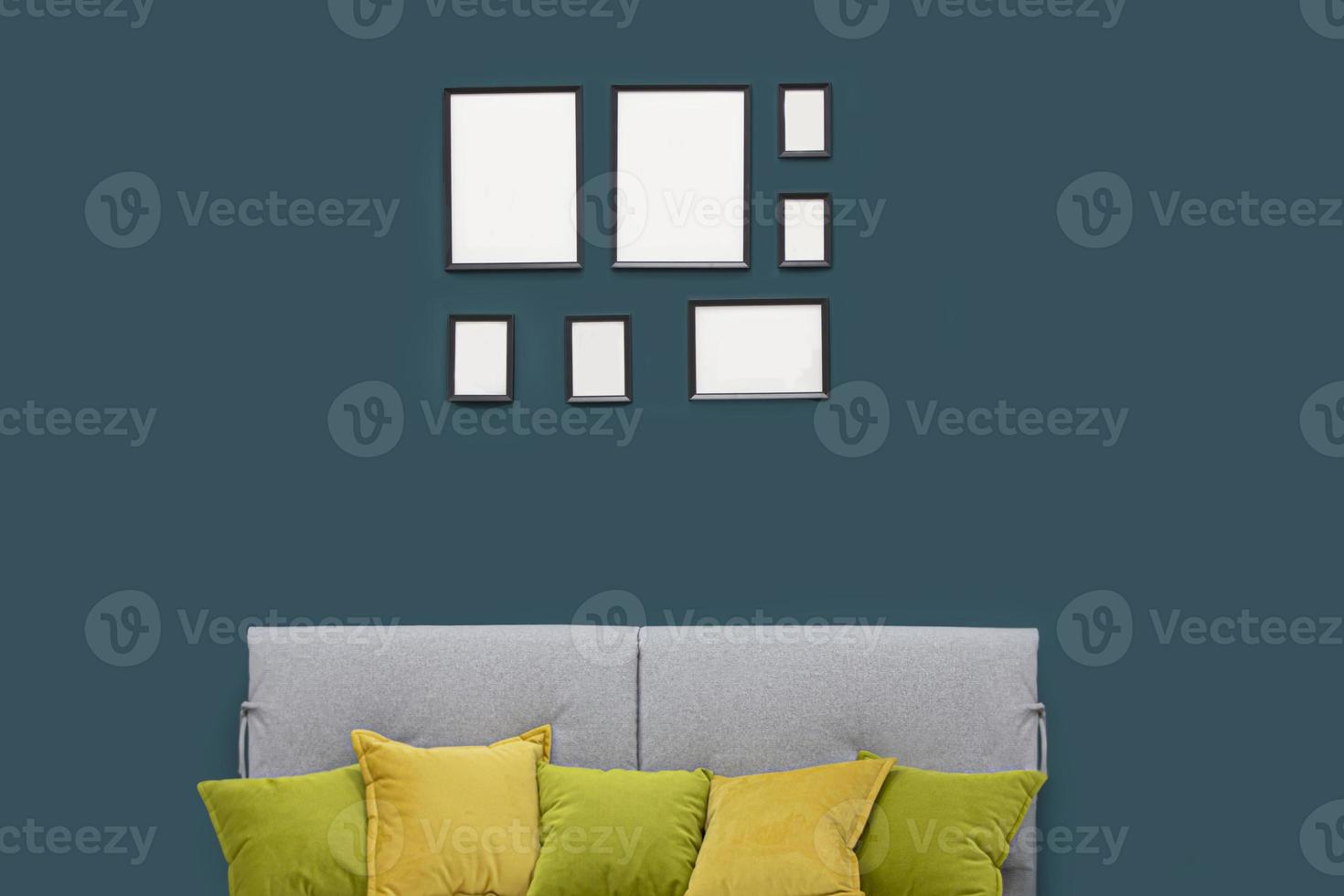 Turquoise wall of the room with empty frames and sofa. photo