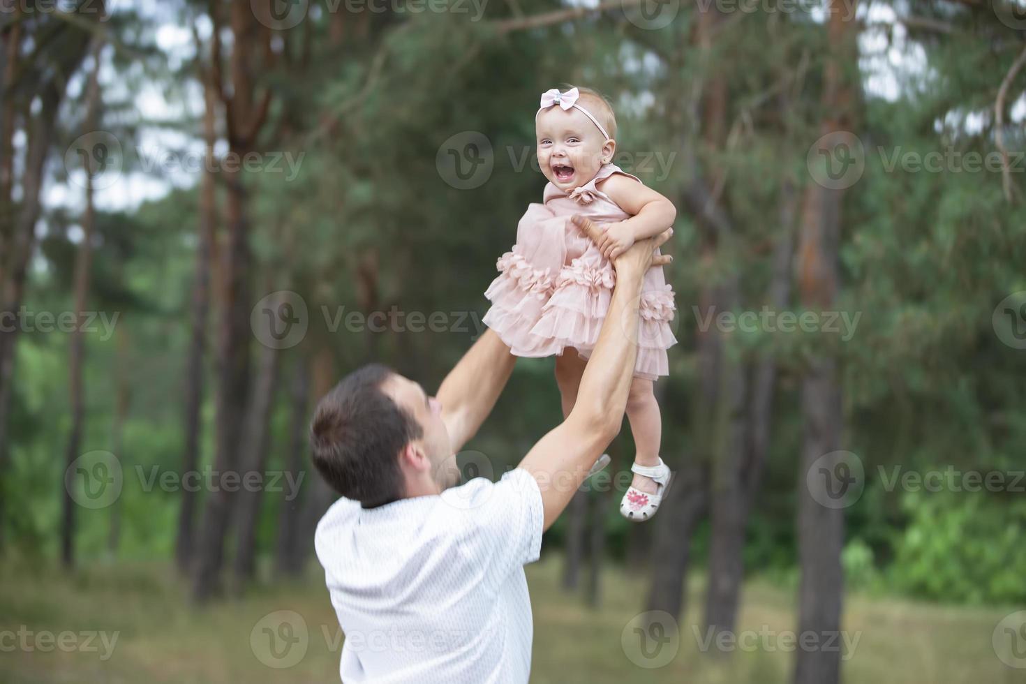 contento papá lanza arriba con su pequeño hija para un caminar. paternidad. foto