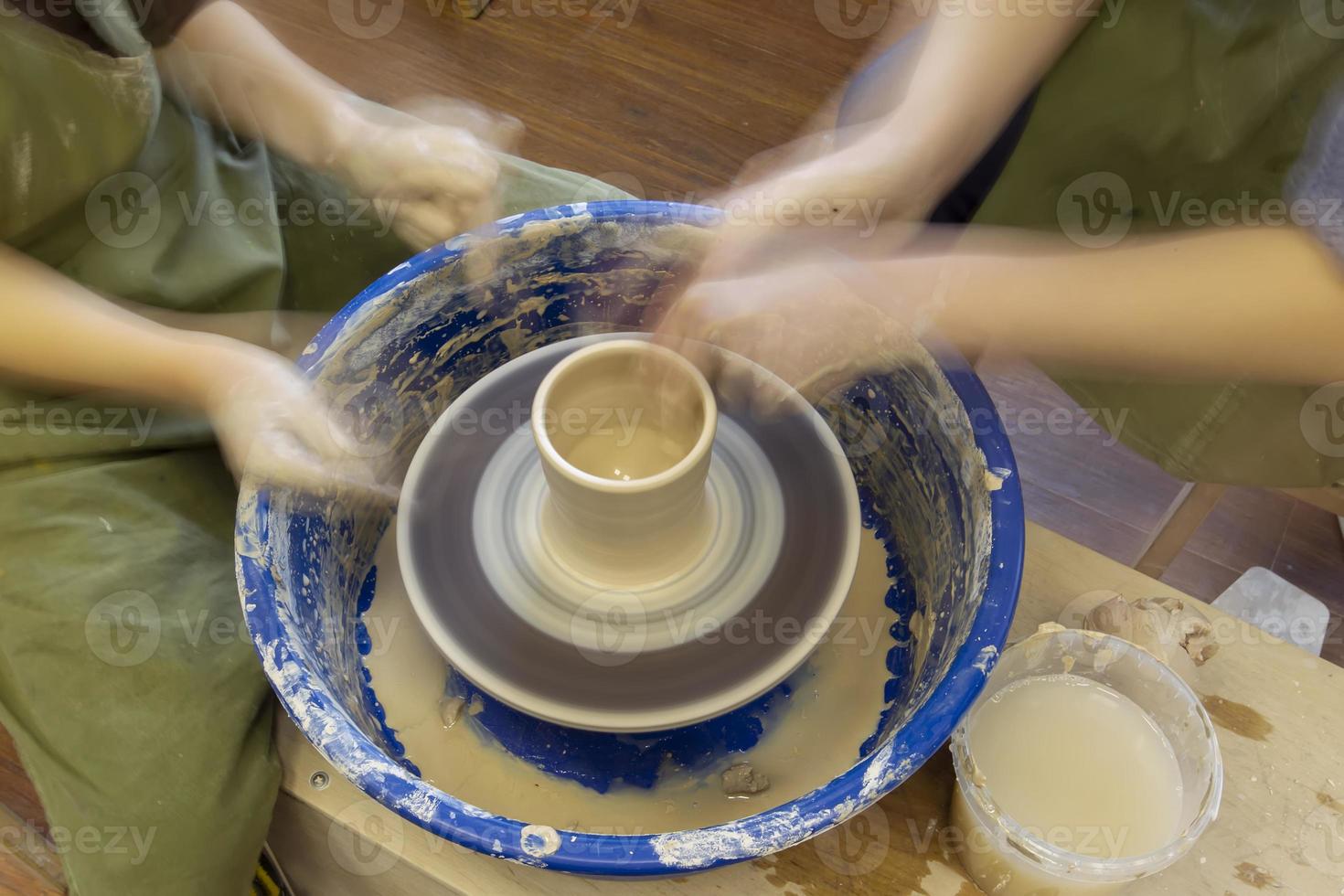 Earthenware on a potter's wheel and the hands of a potter, blurred in motion. Pottery training. photo