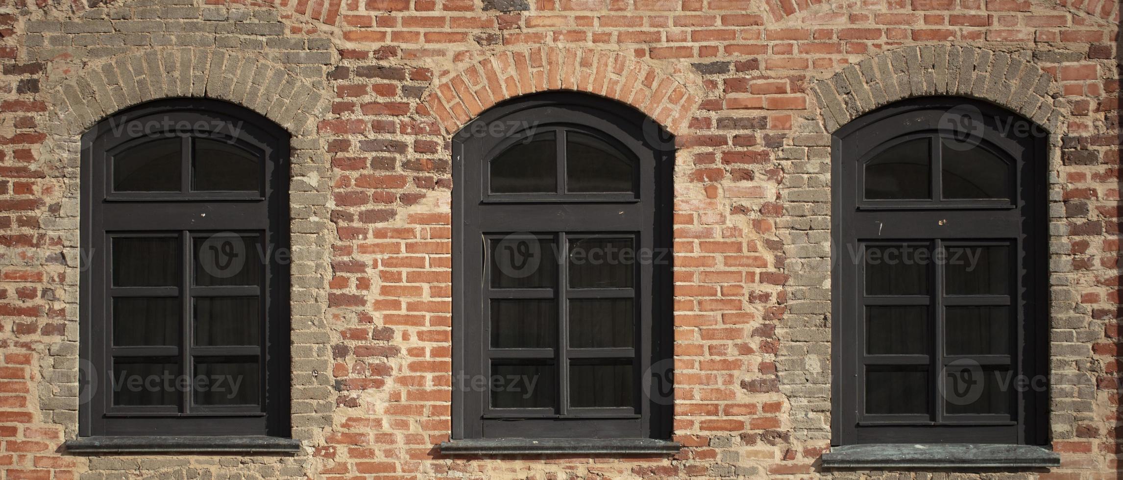 Brick wall of an old building with arched windows. photo