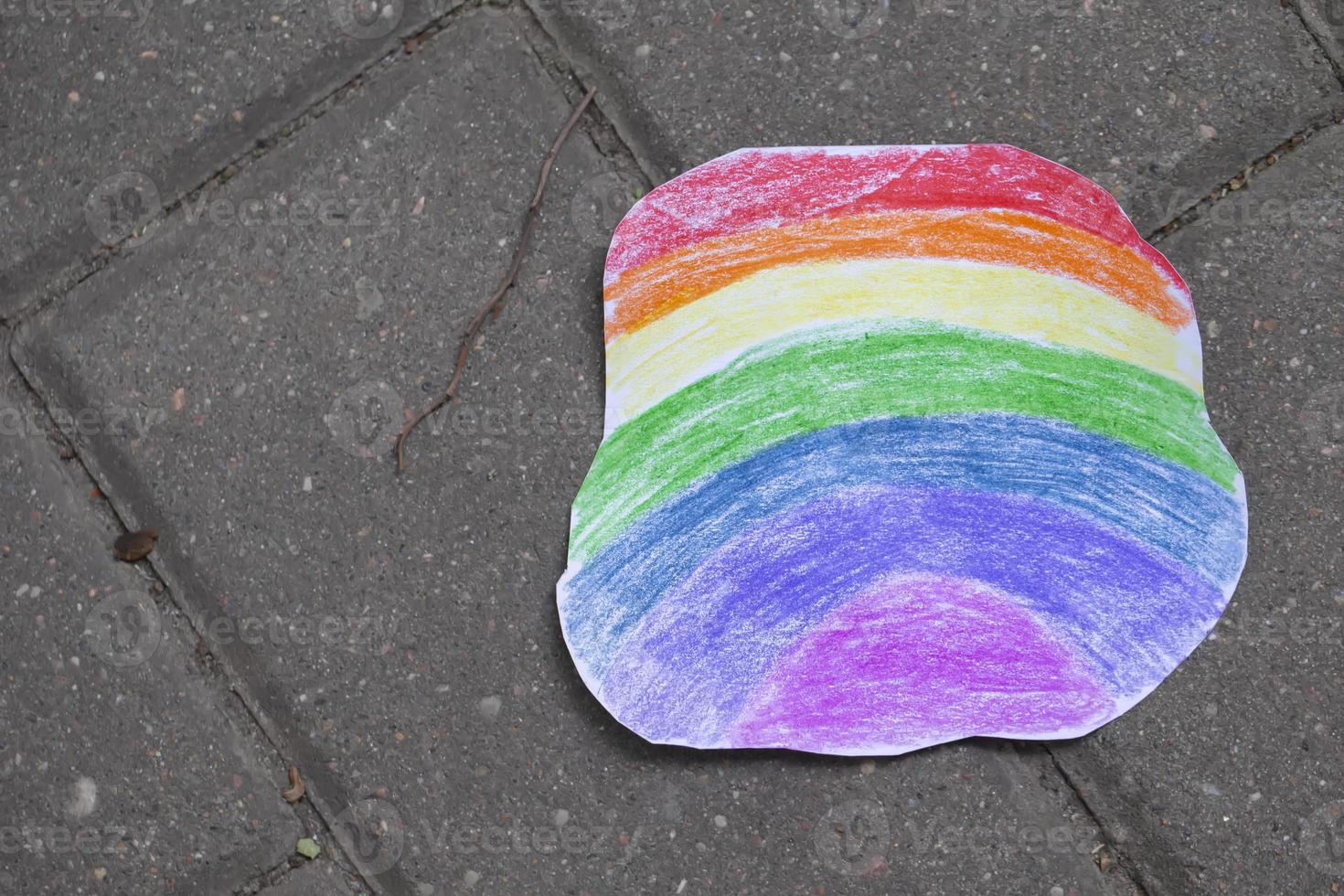 A bright rainbow made of paper colored with colored pencils lies on the asphalt. photo