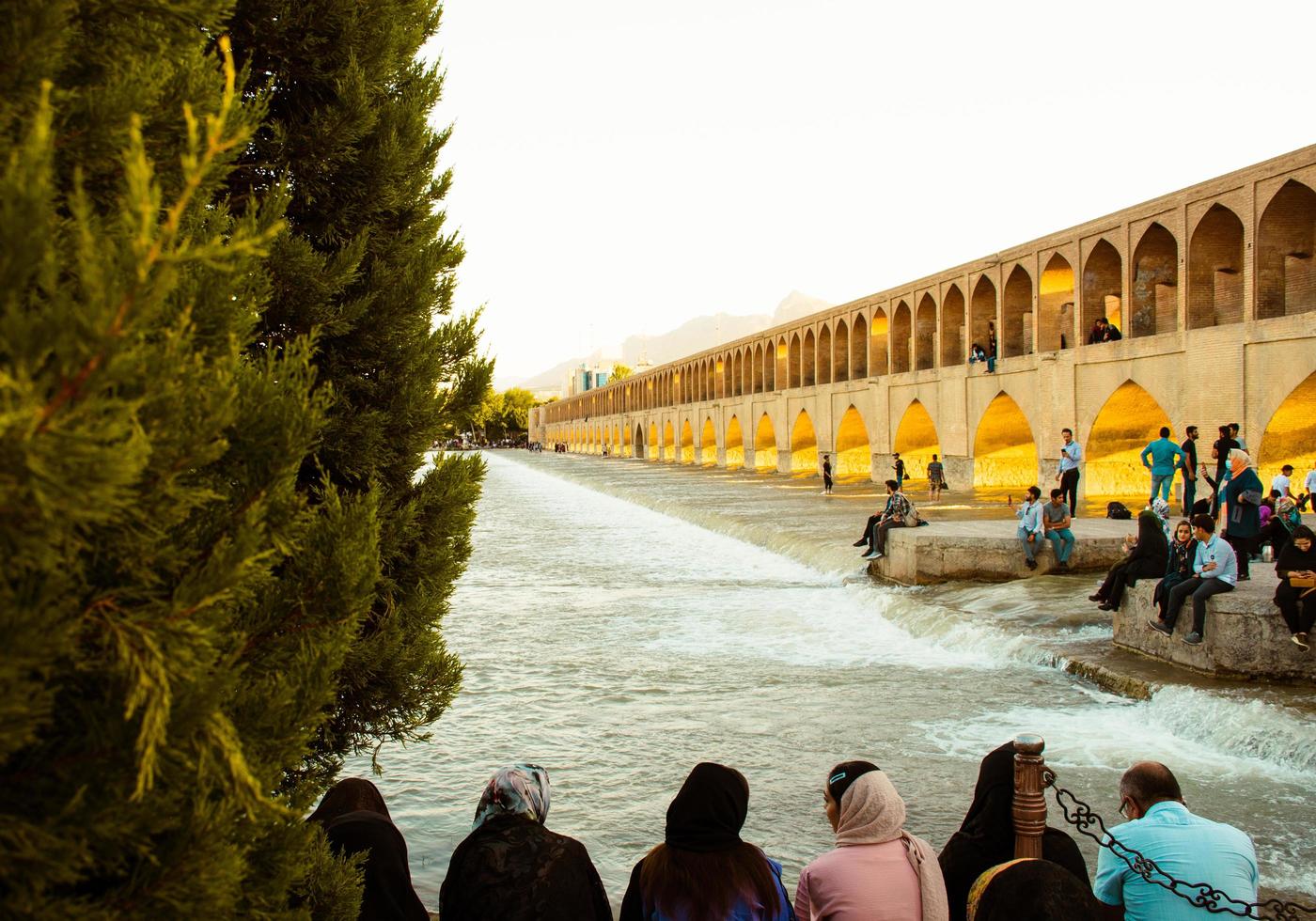 Isfahan, Iran - May 2022 - people chill and socialize around SioSe Pol or Bridge of 33 arches, one of the oldest bridges of Esfahan and longest bridge on Zayandeh River photo