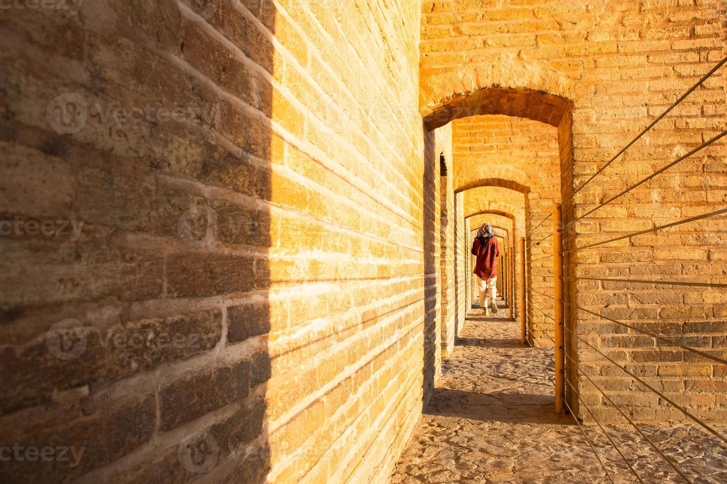 Isfahan, Iran ,2022 - back view woman walk on Sio Se Pol or Bridge of 33 arches, one of the oldest bridges of Esfahan and longest bridge on Zayandeh River photo