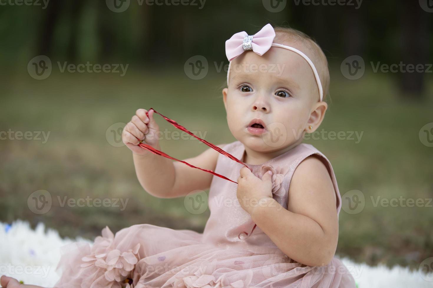 A beautiful little girl on a walk in a summer park. One year old child. Sweet baby. photo