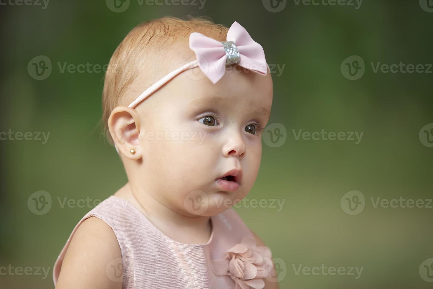 The face of a beautiful little girl on a green background. One year old child. photo