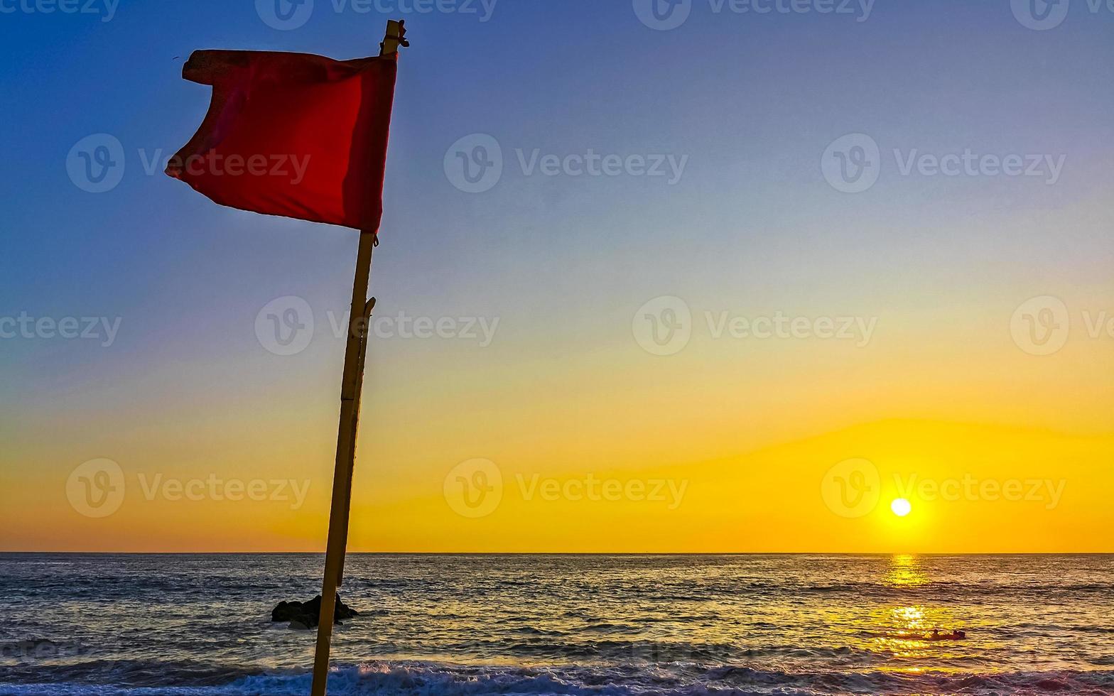 rojo bandera nadando prohibido alto olas con puesta de sol en México. foto