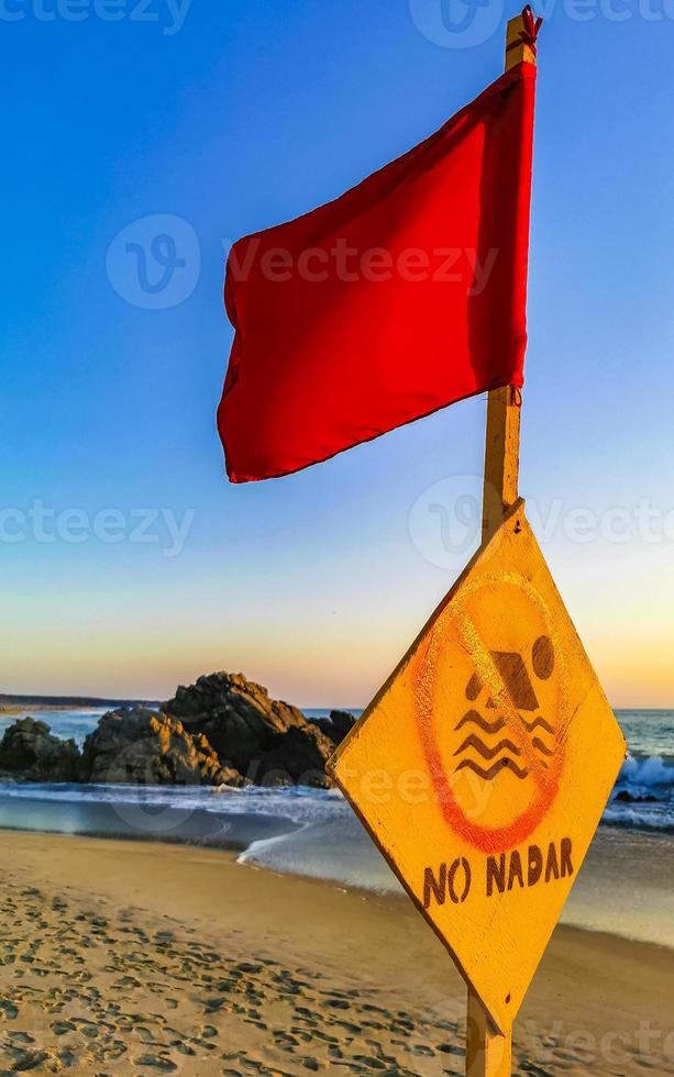 rojo bandera nadando prohibido alto olas con puesta de sol en México. foto