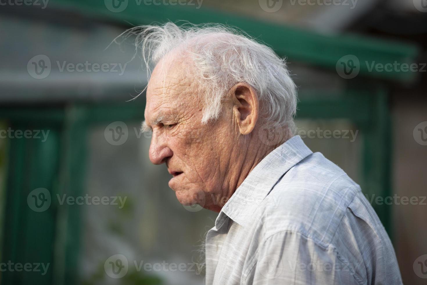 un antiguo canoso hombre con un preocupado cara y arrugas en perfil. foto