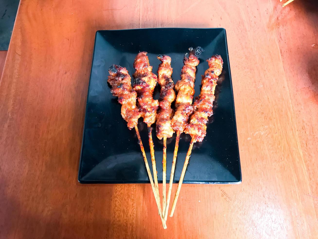 There are five skewers of blushing spicy chicken photo