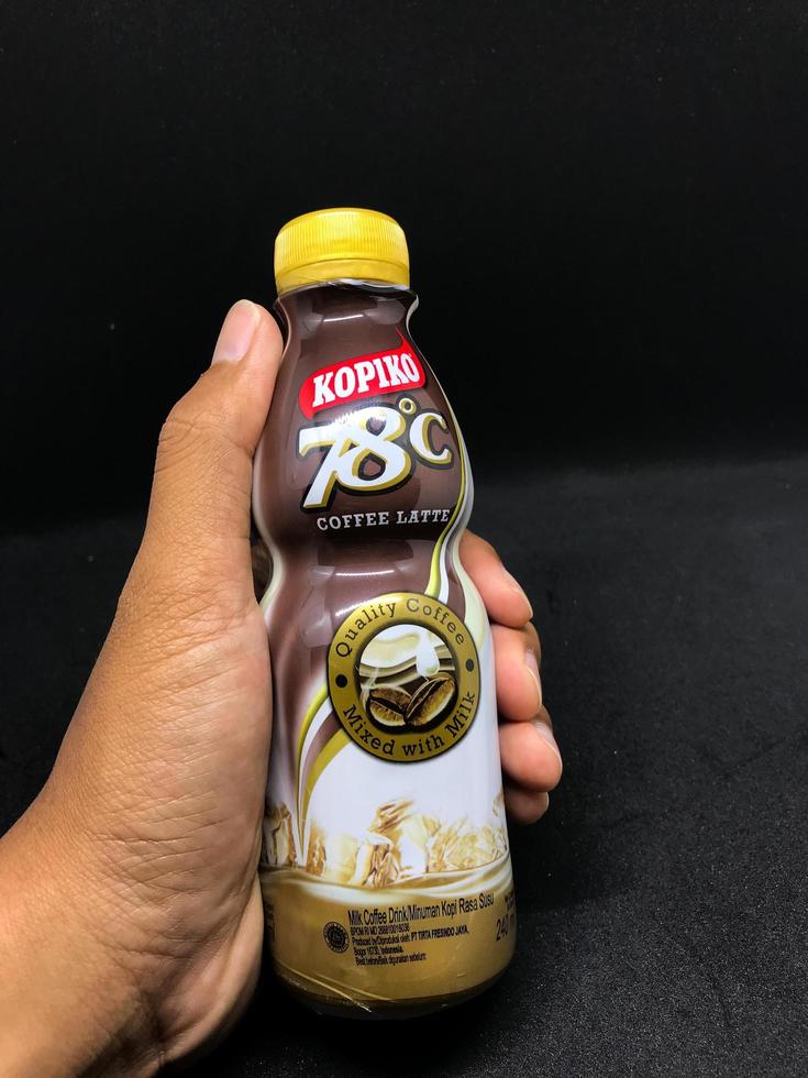 Surakarta, Indonesia. October 13, 2022. Holding a kopiko flavored coffe latte with a black background photo