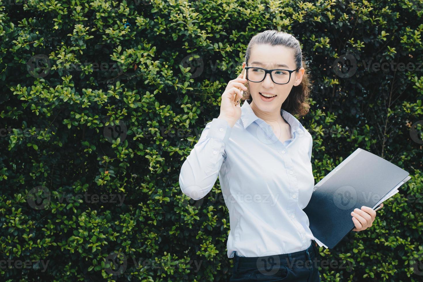 Portrait of young mixed race businesswoman speaking on mobile phone and holding her job document. photo