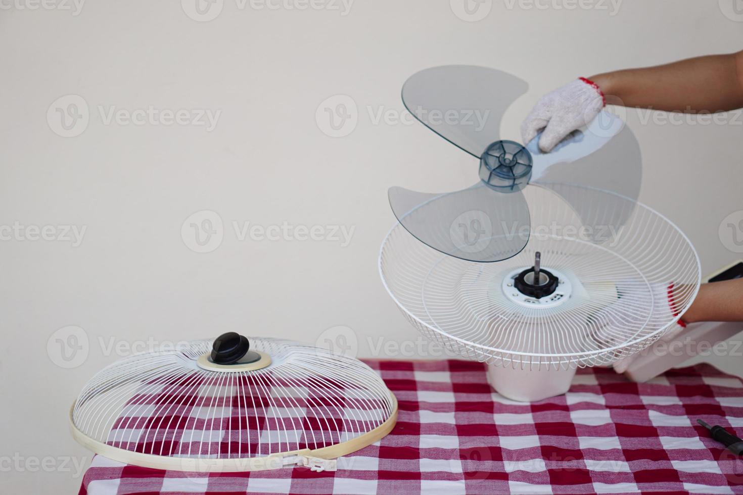 Closeup mechanic hands combine part of electric fan. Concept, maintenace appliance, electric devices in daily life, check ,repair or fix when it has problems for long using. photo