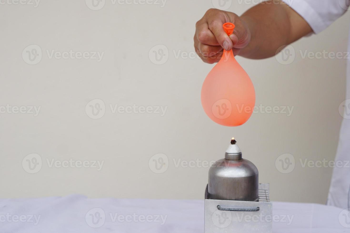 Balloon with water filled is burned on fire flame of metal lantern. Concept, science experiment. Fireproof balloon demonstration. Classroom activity, Education lesson. Learning by doing, observe, test photo