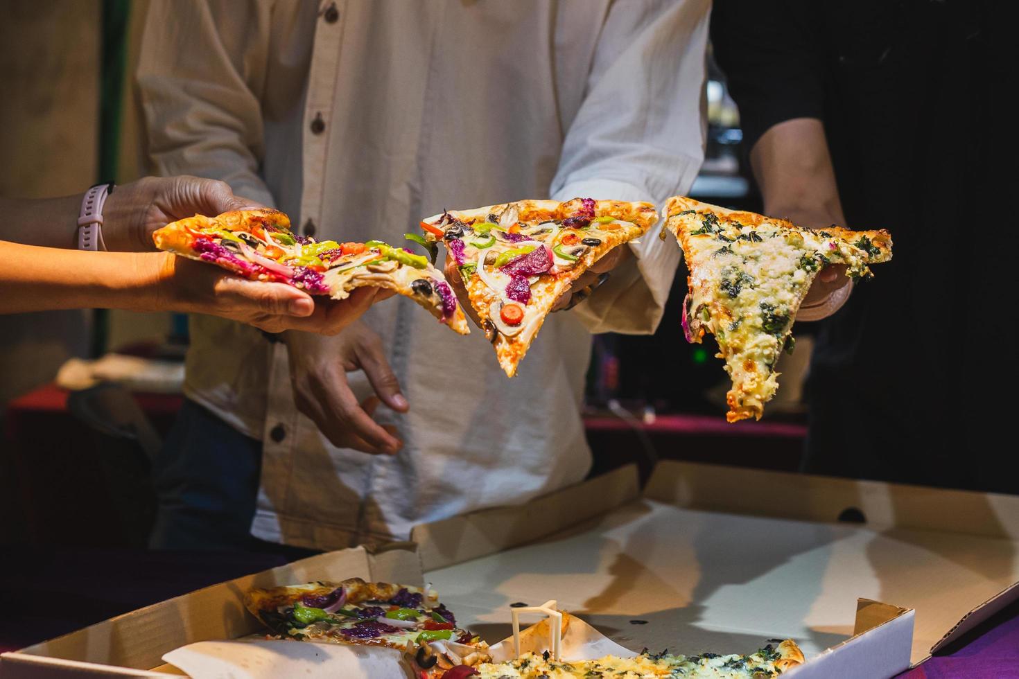 Group of unrecognizable peoples hands holding a slice of pizza. photo