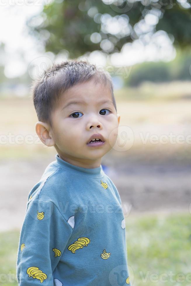 Portrait of a little boy looking into the camera. Children's emotions. Boy with black eyes playing outdoors. Happy Asian child toddler boy smiling close up looking at camera. Education Concept. photo