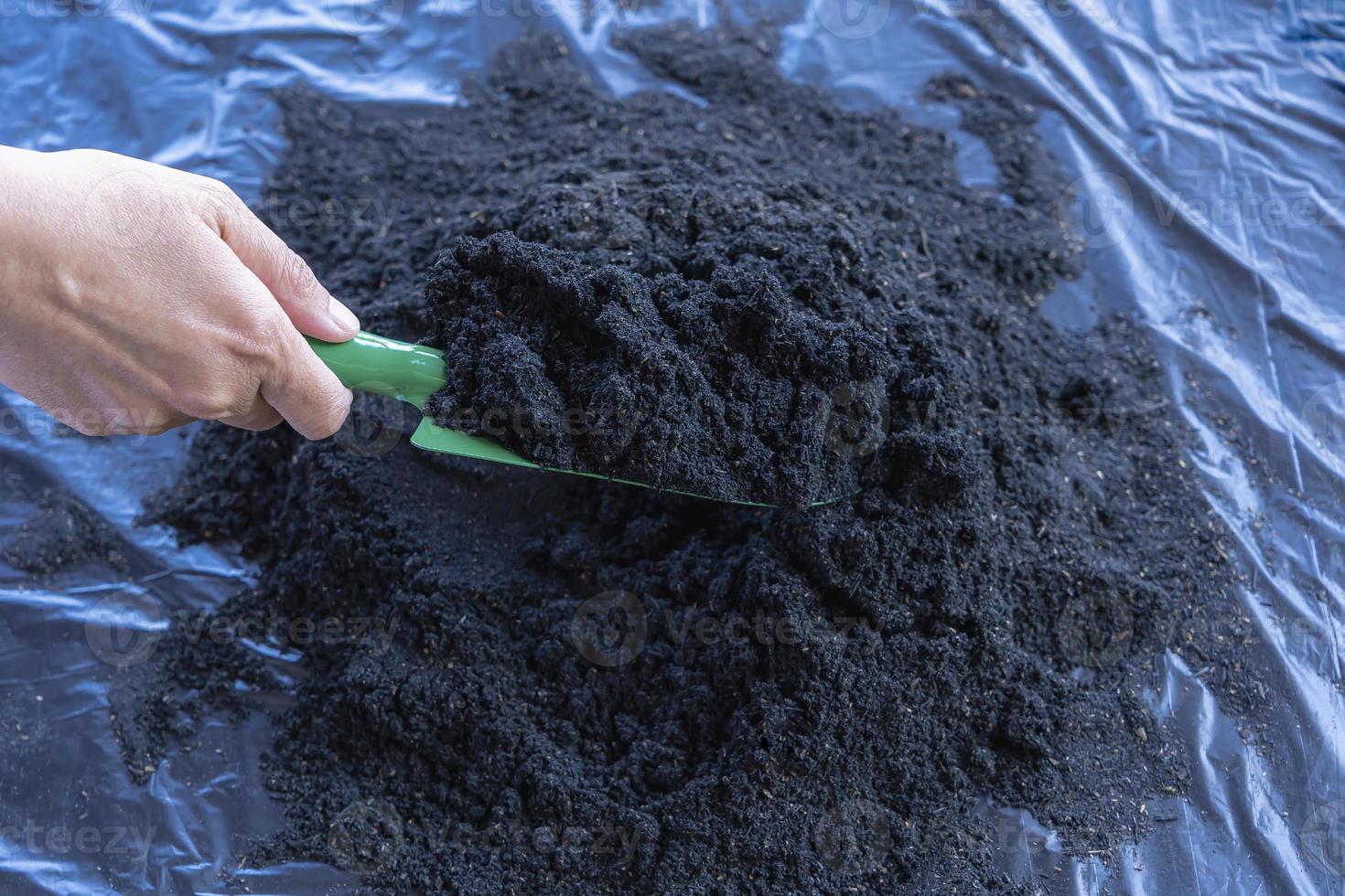 Preparation of soil mixture from fertile compost, humus and vermiculite on  black garbage bag floor in garden. Mixing the soil components for the preparation of the substrate for transplanting plants. photo