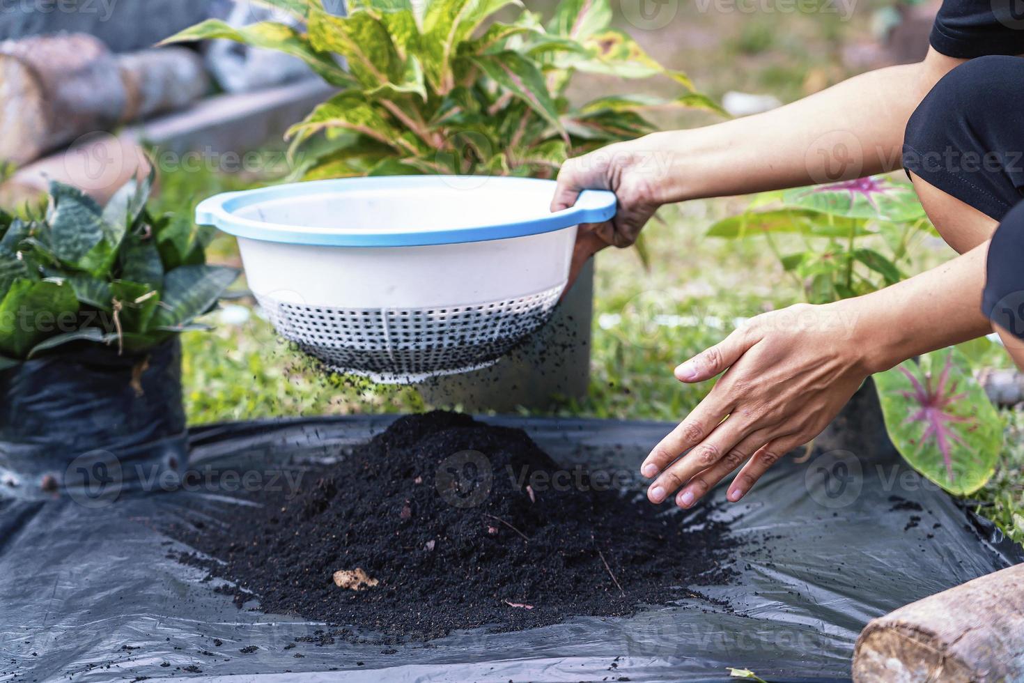 preparación de una mezcla de suelo a partir de compost fértil, humus y vermiculita en el suelo de una bolsa de basura negra en el jardín. mezclar los componentes del suelo para la preparación del sustrato para trasplantar plantas. foto