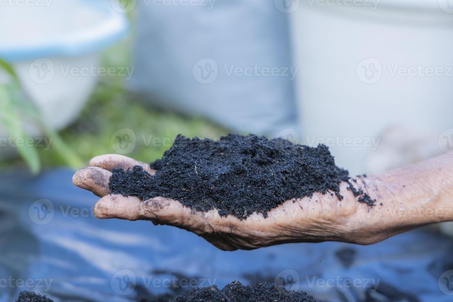 Hands holding abundance soil for agriculture or preparing to plant  Testing soil samples on hands with soil ground background. Dirt quality and farming concept. Selective focus on black soil in front photo