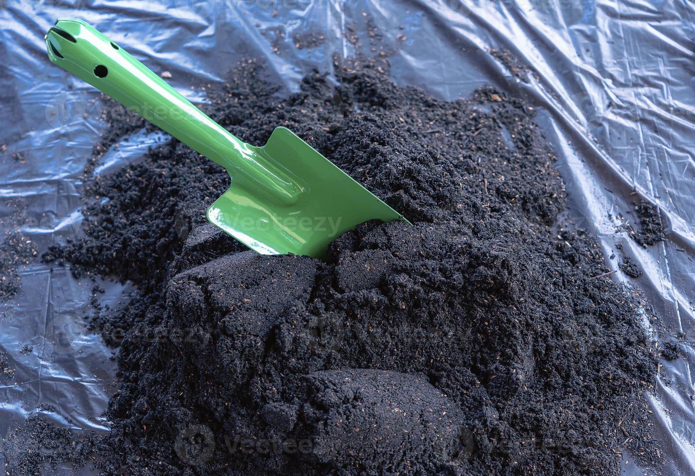 Preparation of soil mixture from fertile compost, humus and vermiculite on  black garbage bag floor in garden. Mixing the soil components for the preparation of the substrate for transplanting plants. photo