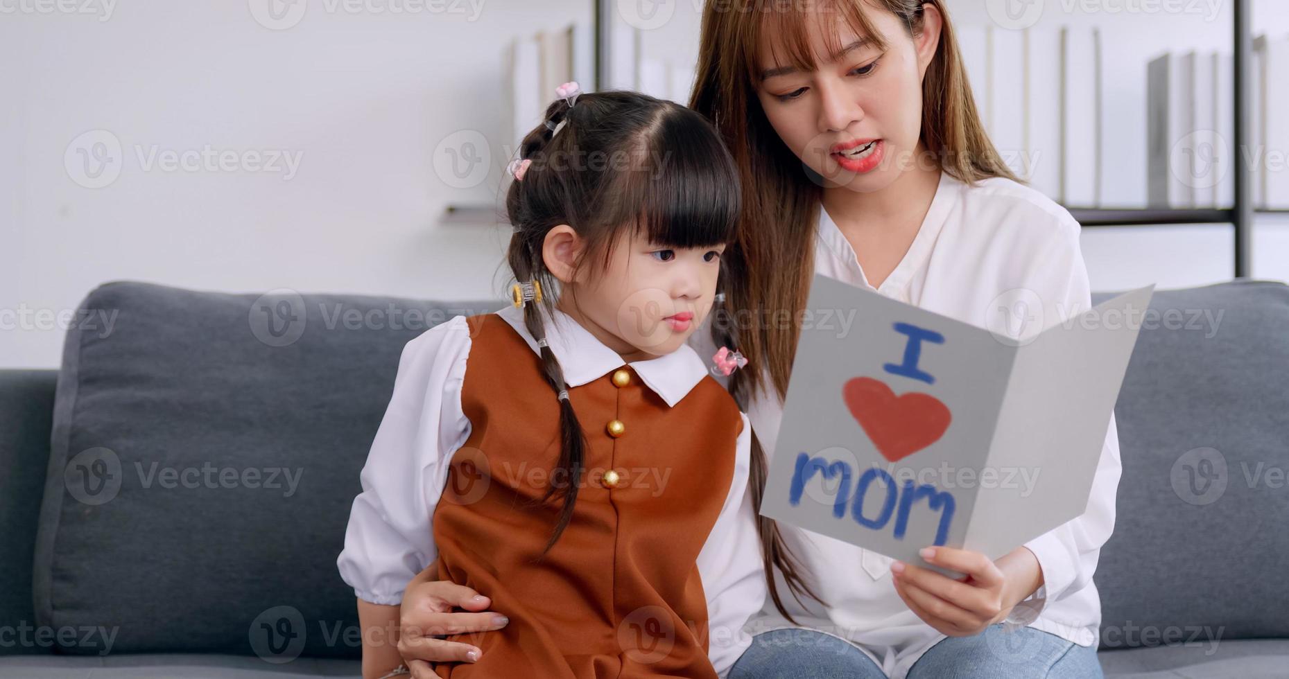 A little daughter giving mom handmade greeting card and wishing her Happy Mother's Day. photo