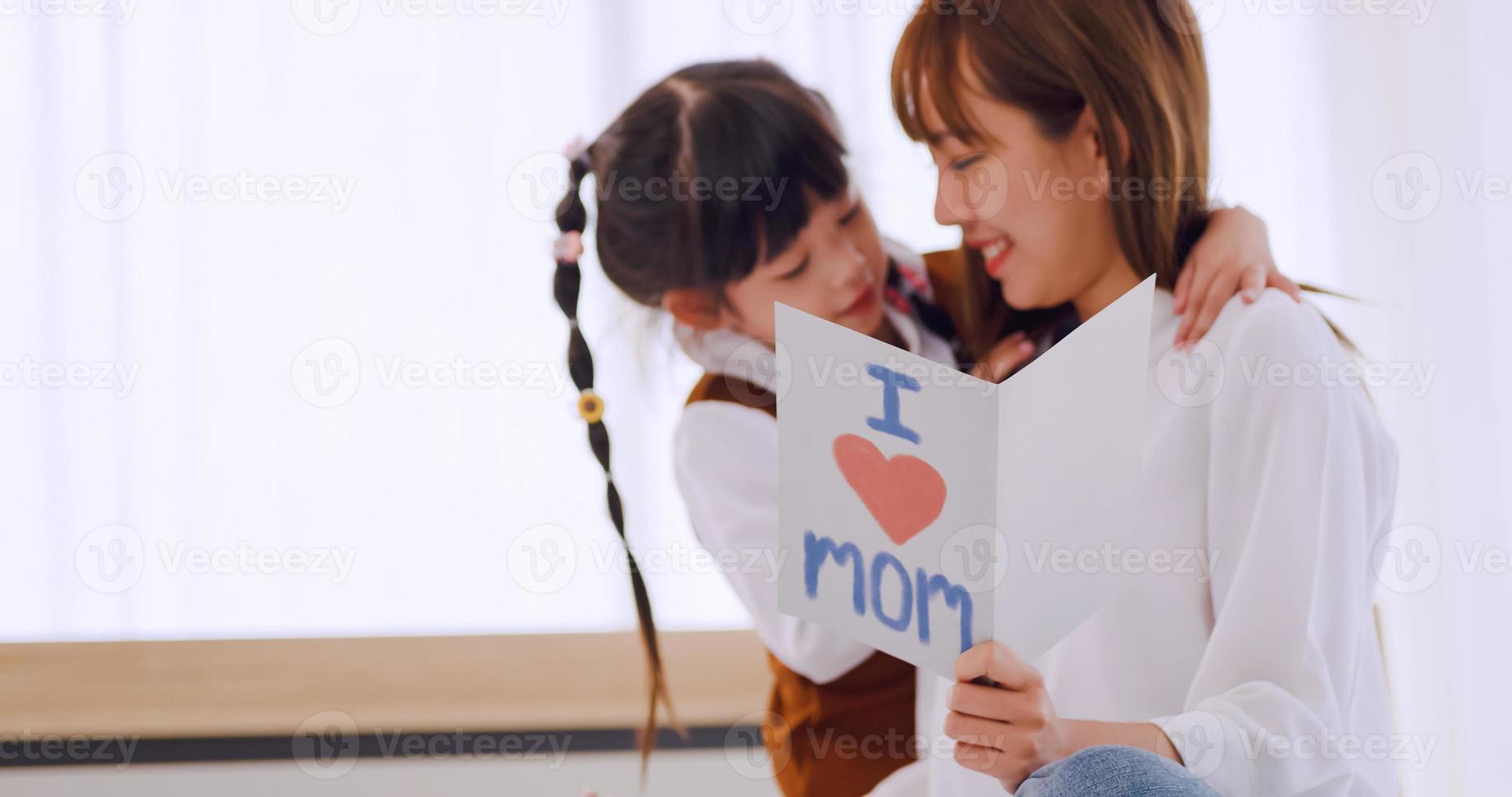 A little daughter giving mom handmade greeting card and wishing her Happy Mother's Day. photo