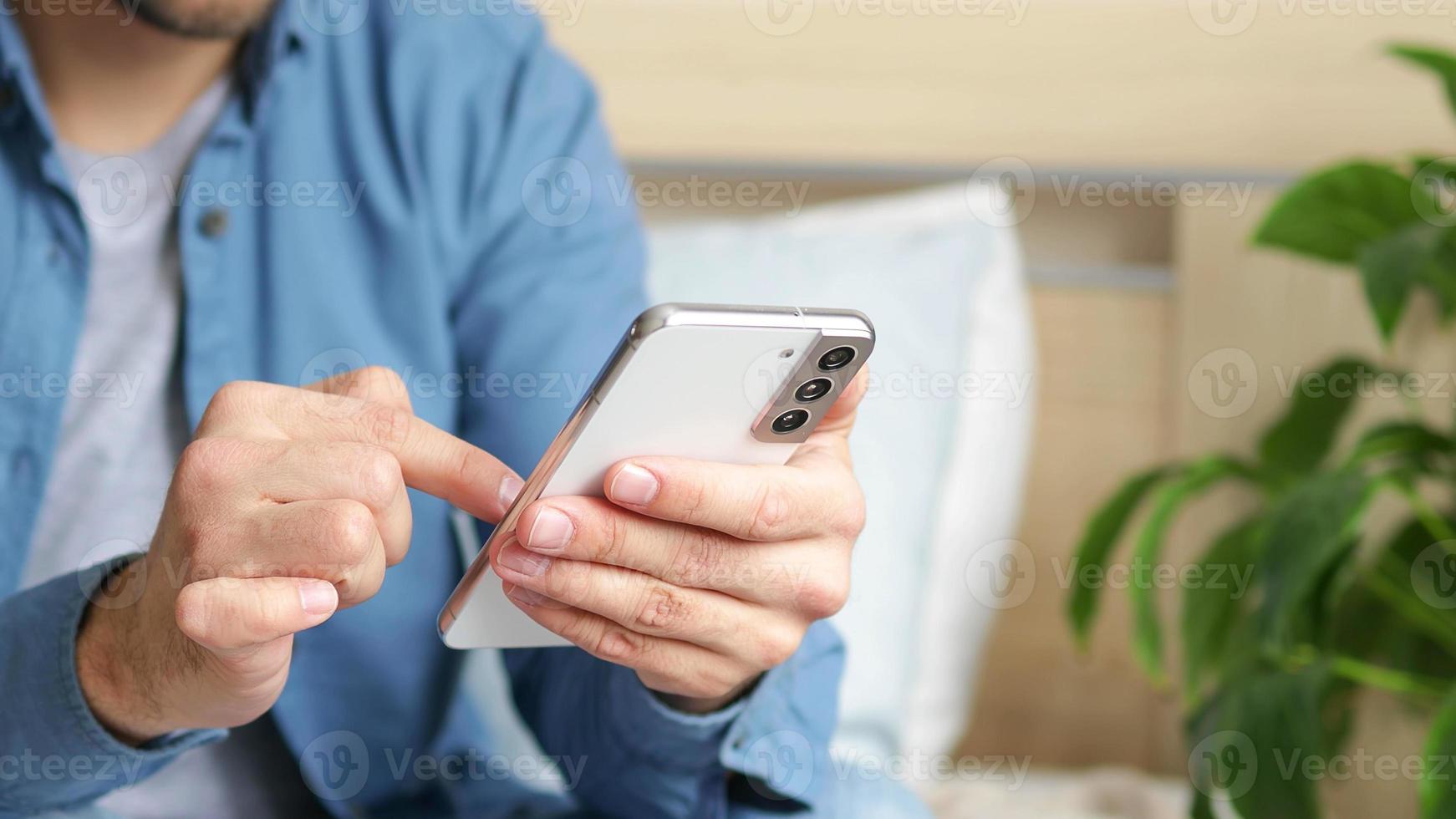 A man using a smartphone presses with his finger, reads social networks on the Internet, typing text or shopping online photo