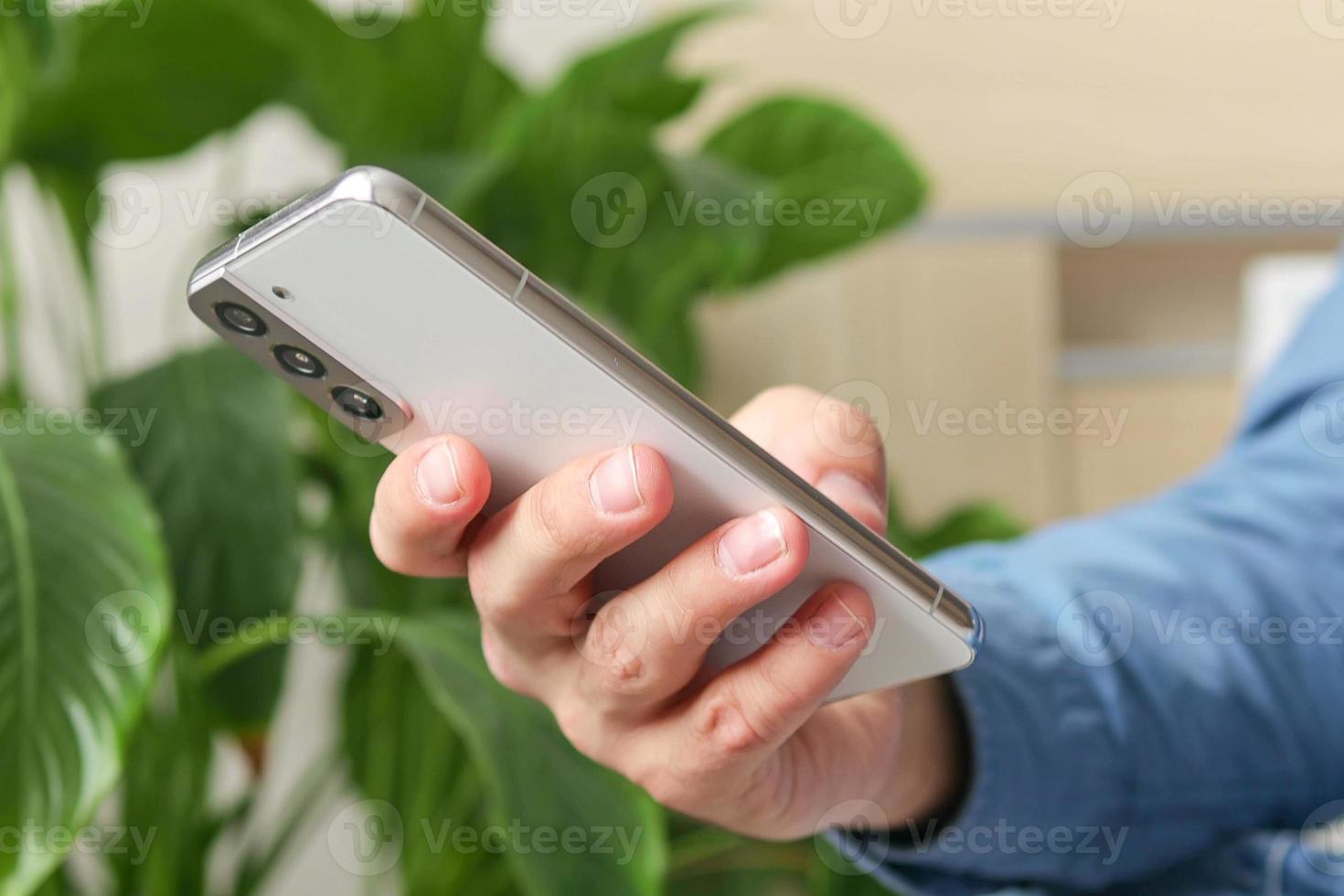 Close up of male hands using smartphone in home interior, search or social media concept, man typing sms message to his friends photo