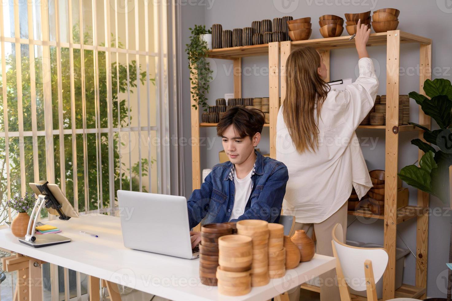 A young couple entrepreneur checking and packaging craft products selling to customers in them shop photo