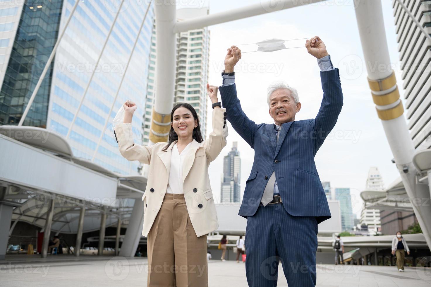 Asian senior mature middle aged businessman and young businesswoman taking mask off in modern city photo