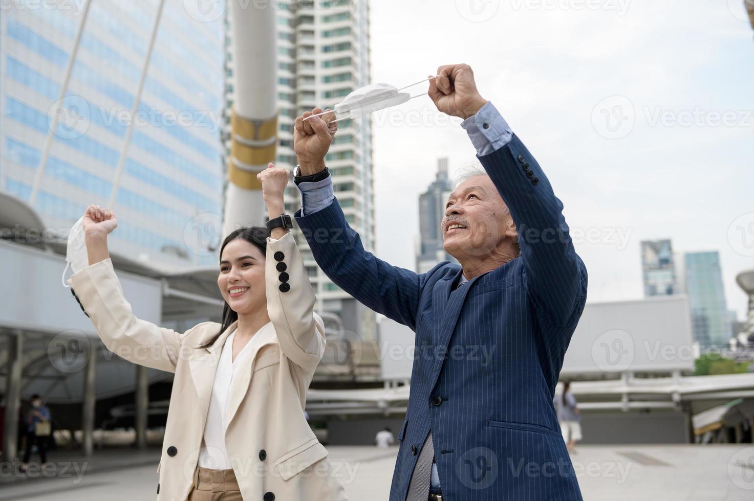 Asian senior mature middle aged businessman and young businesswoman taking mask off in modern city photo