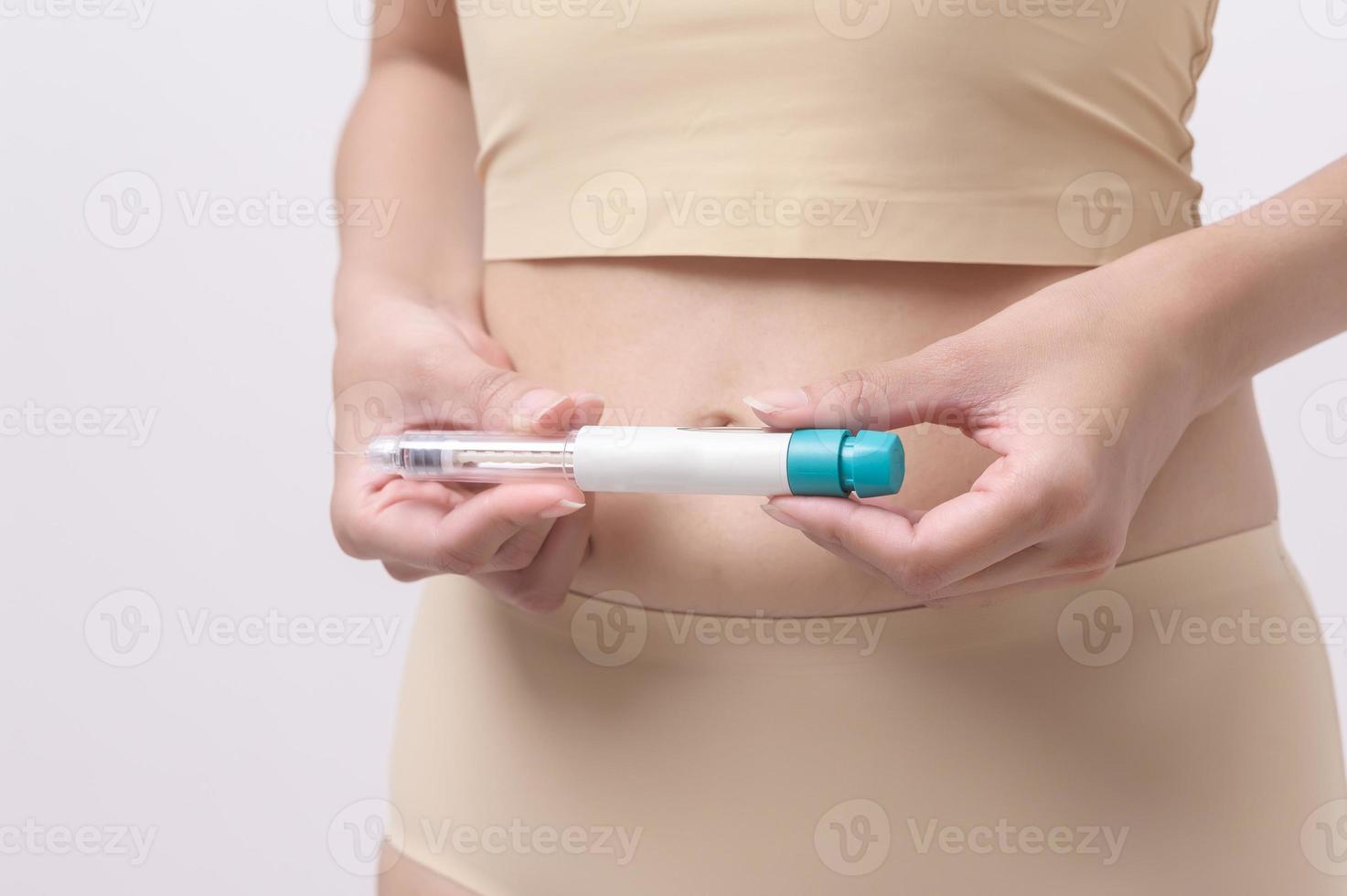 Close up woman using IVF treatment injection on belly to prepare reproductive fertility , Ovulation stimulation . photo