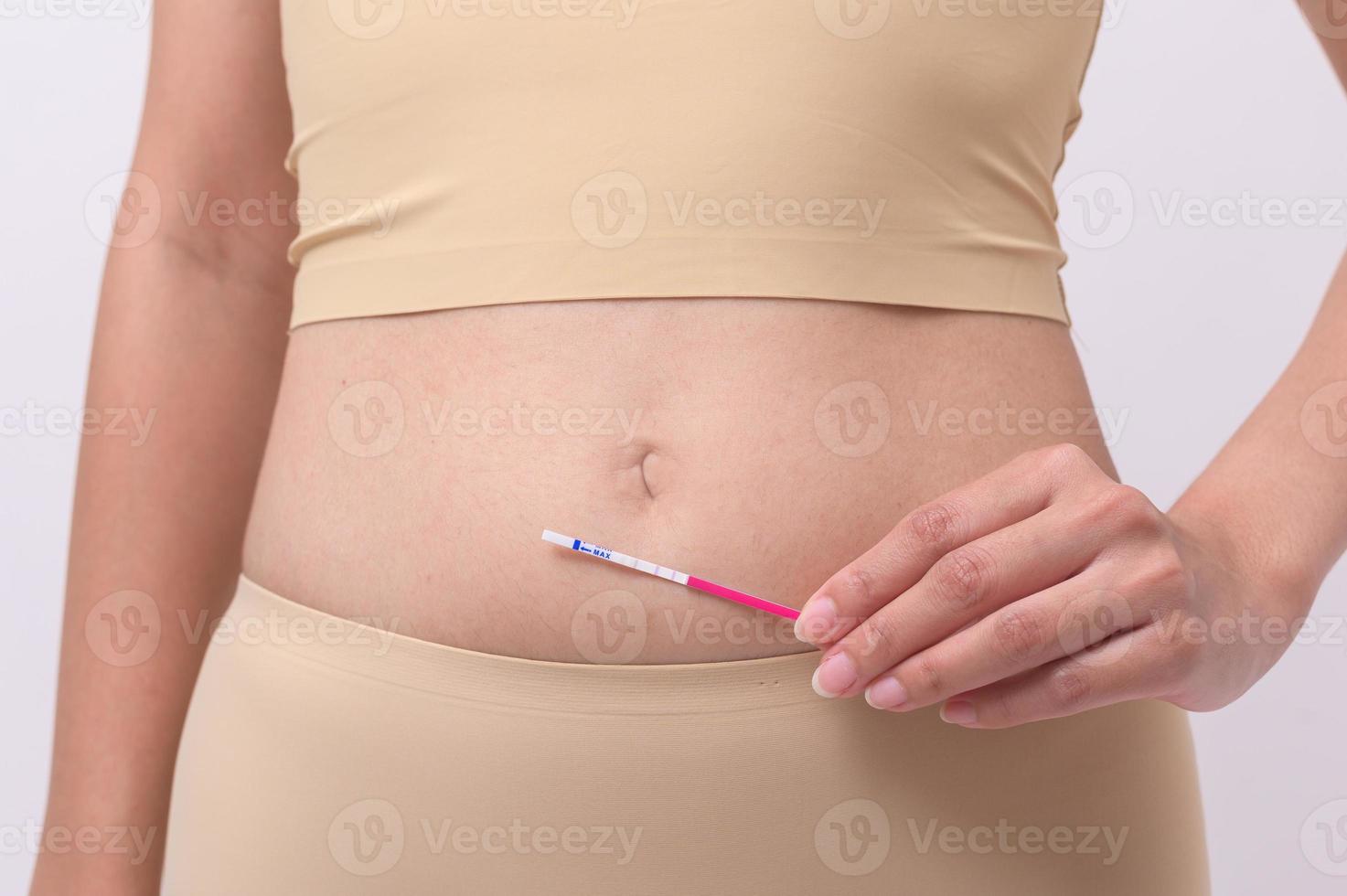 Close up woman using Ovalation LH test  or HCG Pregnancy test on white background photo