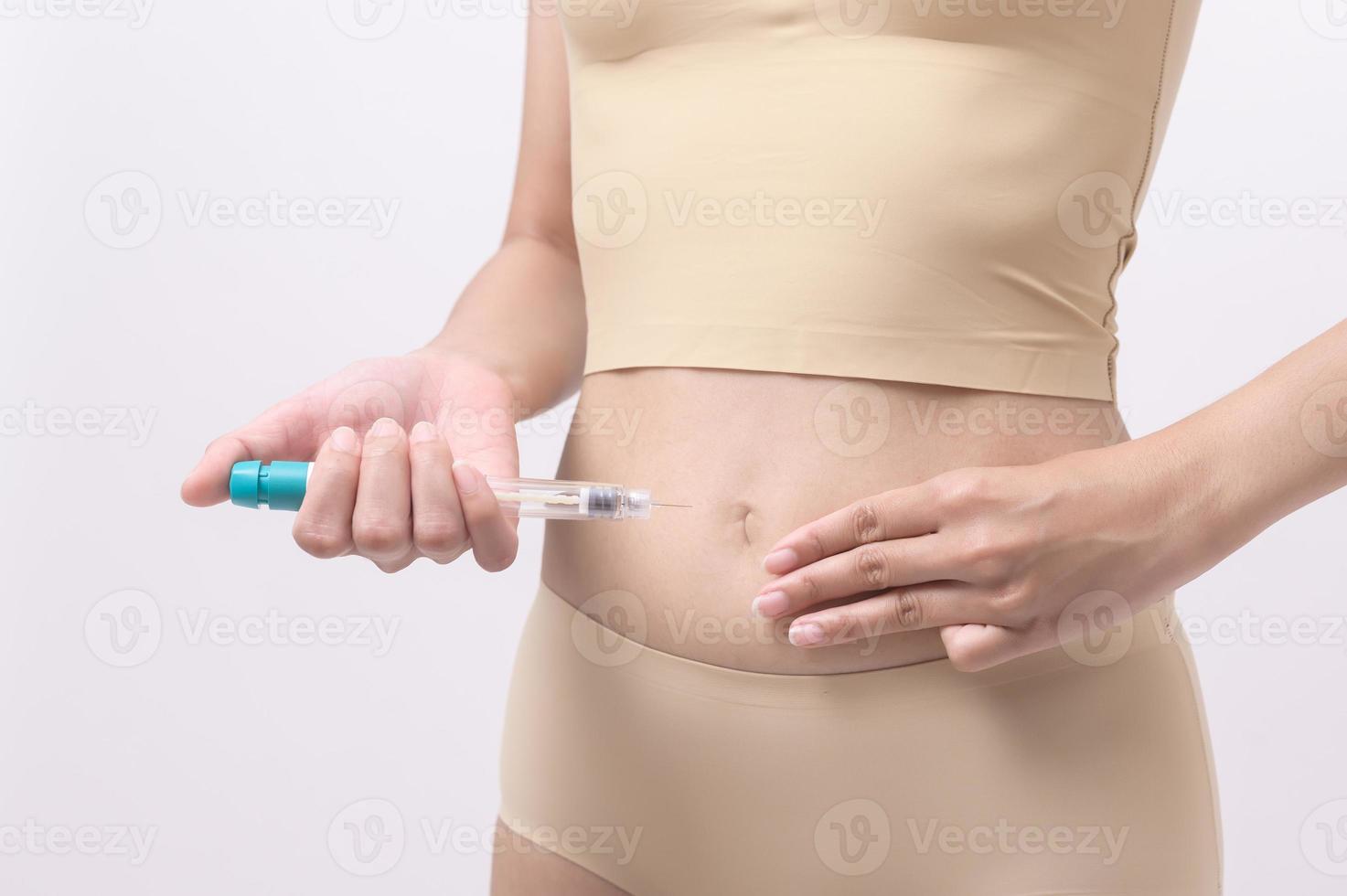 Close up woman using IVF treatment injection on belly to prepare reproductive fertility , Ovulation stimulation . photo