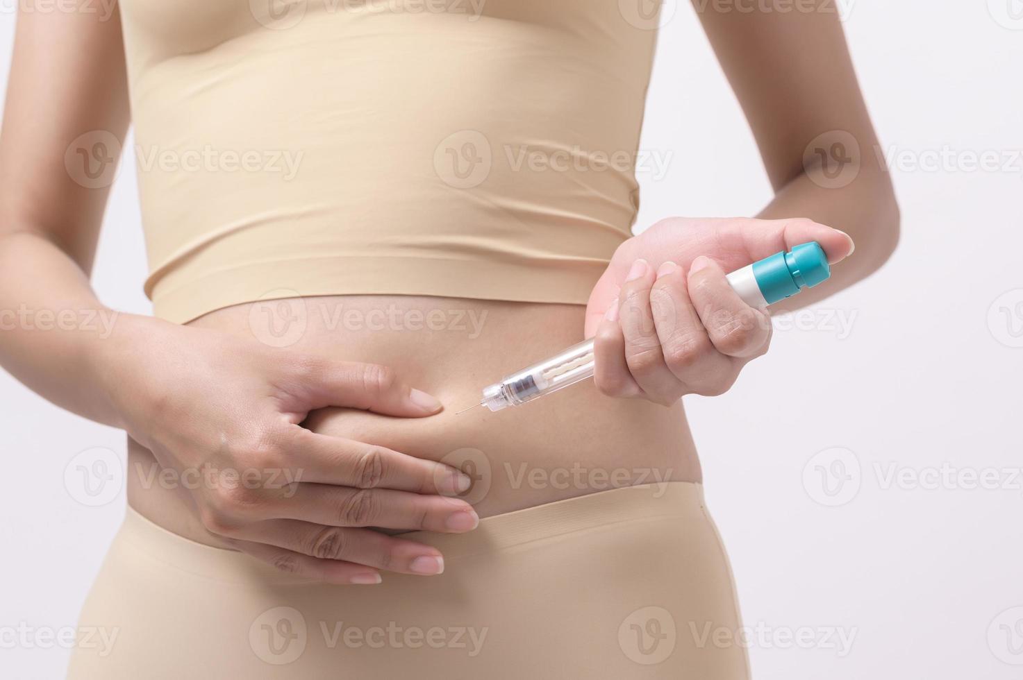 Close up woman using IVF treatment injection on belly to prepare reproductive fertility , Ovulation stimulation . photo