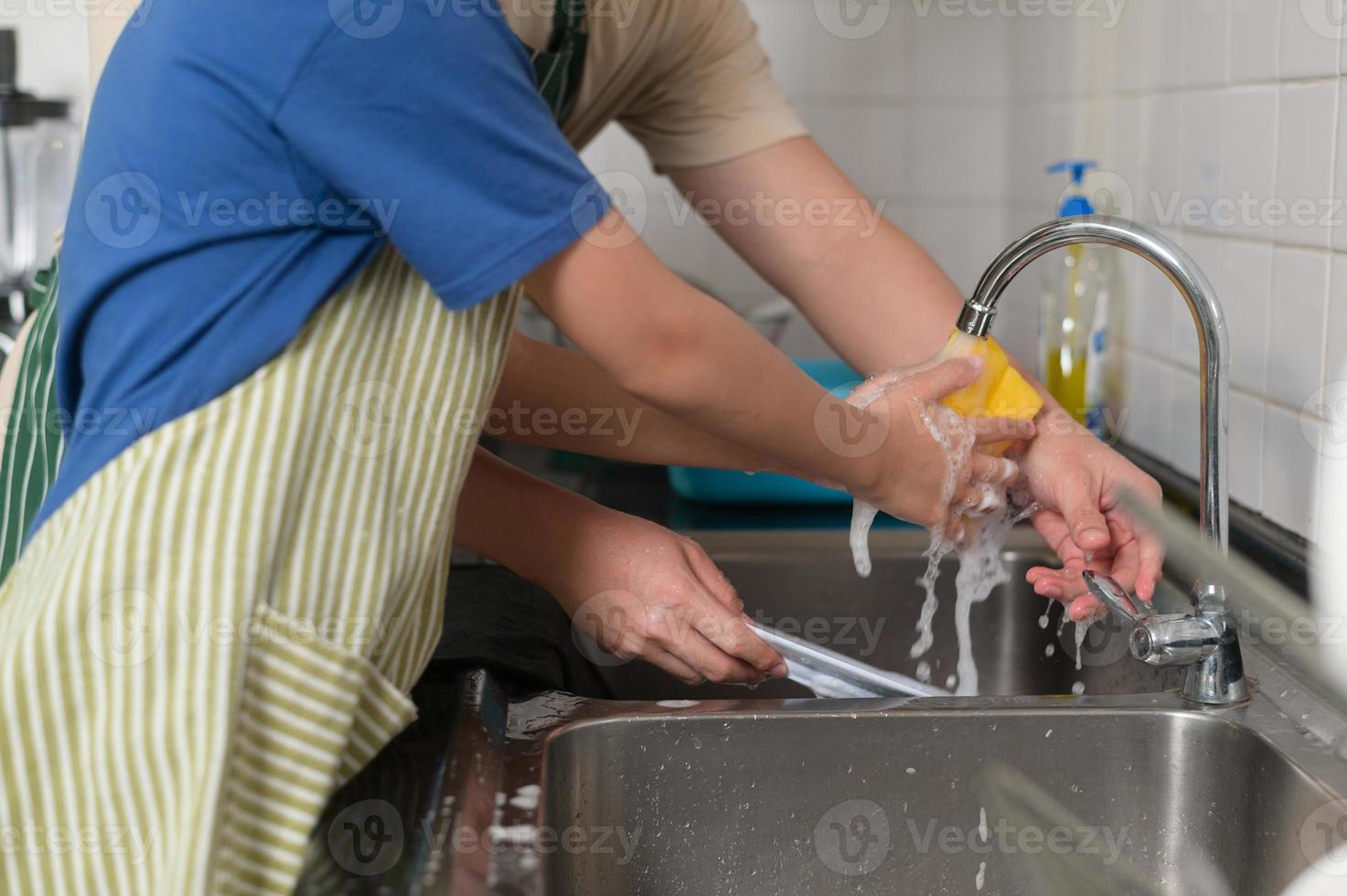 Happy smiling Young Asian father and son washing dishes in kitchen at home photo