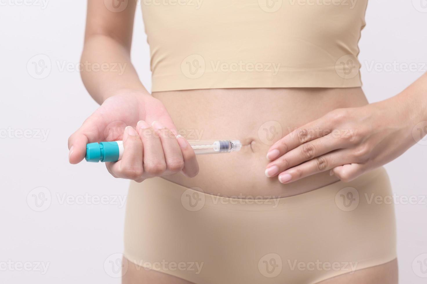 Close up woman using IVF treatment injection on belly to prepare reproductive fertility , Ovulation stimulation . photo