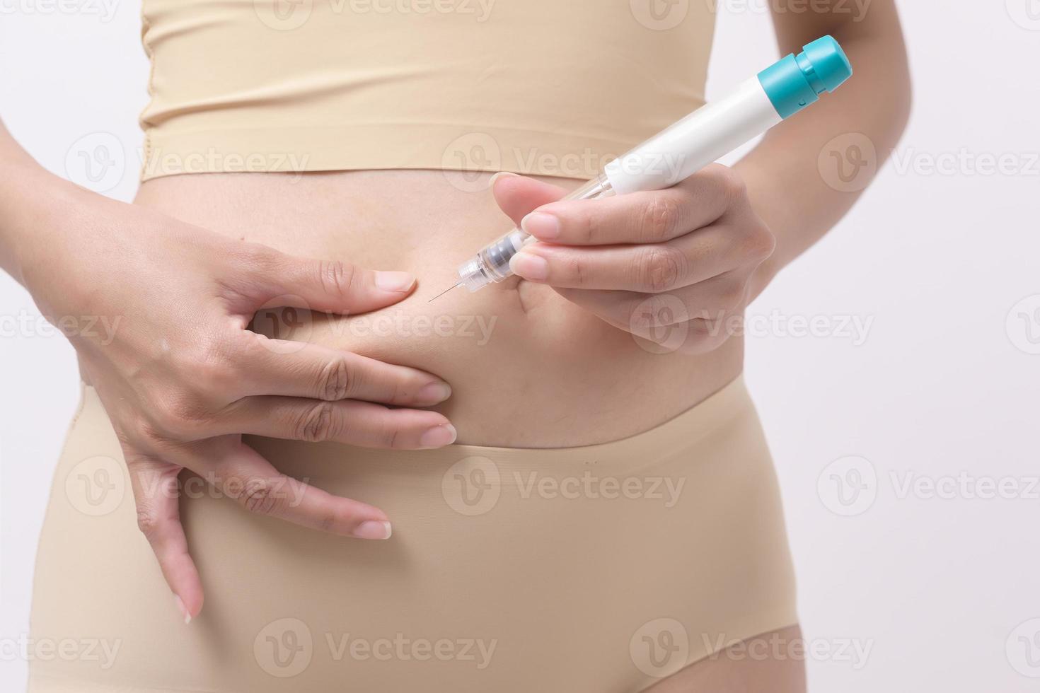 Close up woman using IVF treatment injection on belly to prepare reproductive fertility , Ovulation stimulation . photo
