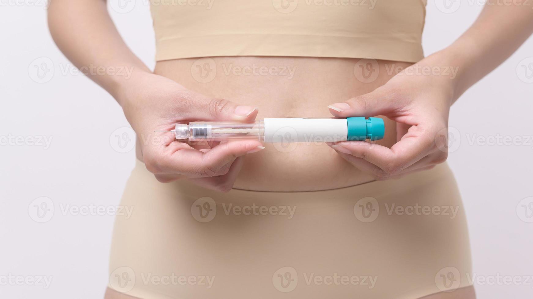 Close up woman using IVF treatment injection on belly to prepare reproductive fertility , Ovulation stimulation . photo