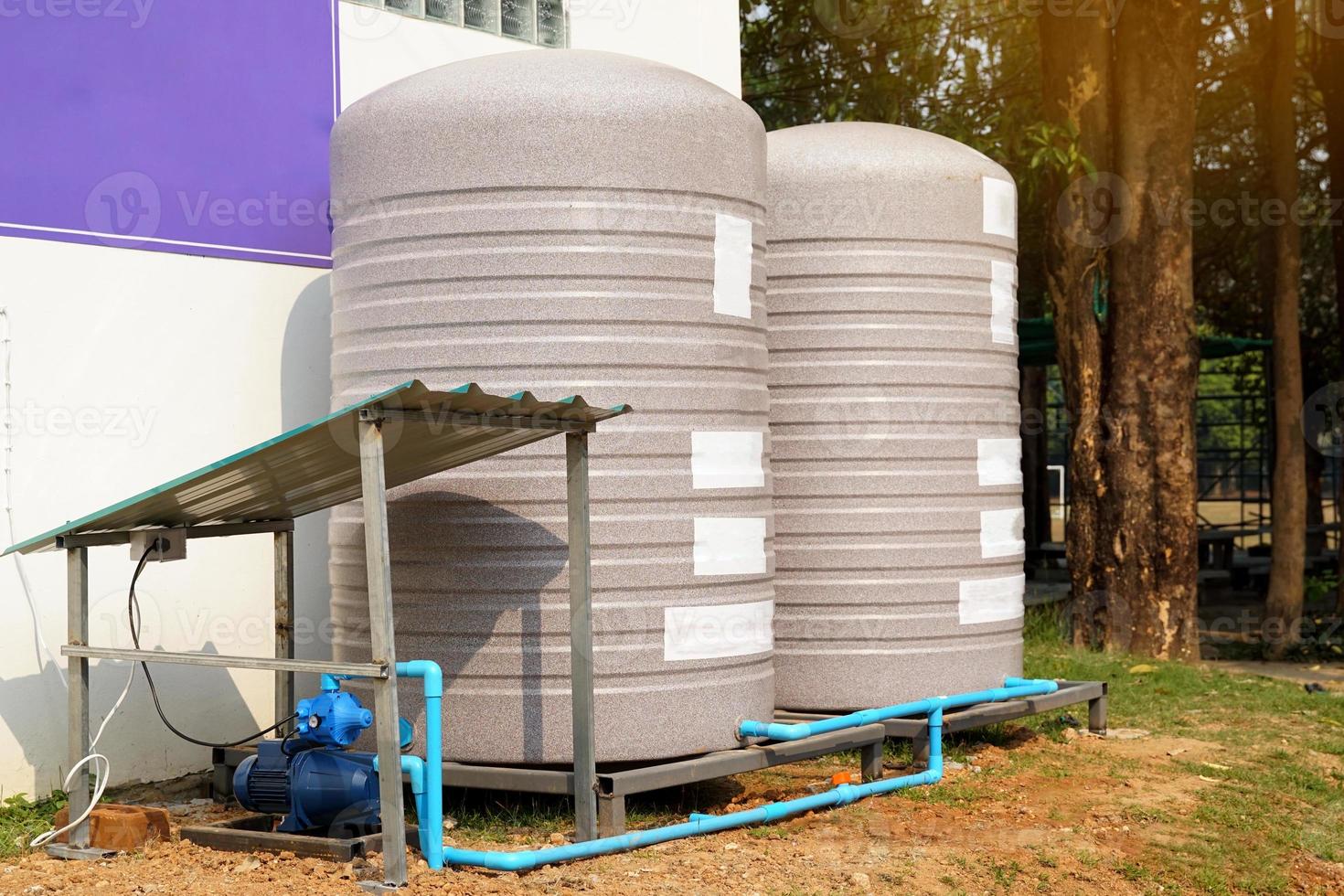 water tank and water pump installed outside the building. For use as a reserve of water for use in homes and offices. Made of special grade material, extra thick, UV protection and not moss. photo