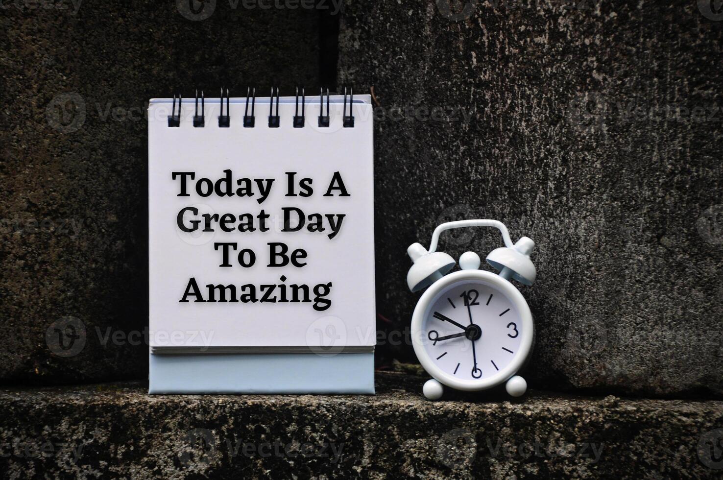 Motivational and inspirational quote on notepad - Today is a great day to be amazing. With rock and alarm clock background. photo