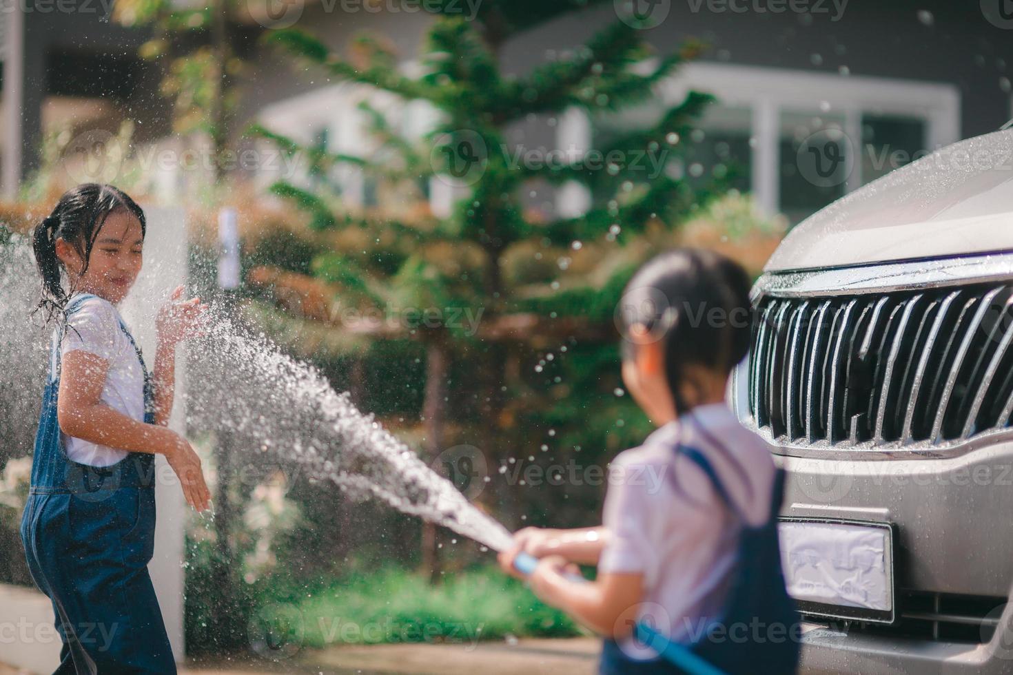 Sibling Asian girls wash their cars and have fun playing indoors on a hot summer day. photo