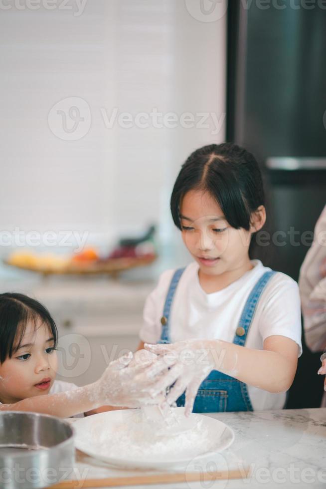 Two little cute Asian girls, learning how to make bread and bakery with a curious and happy smile face. She learns and plays photo