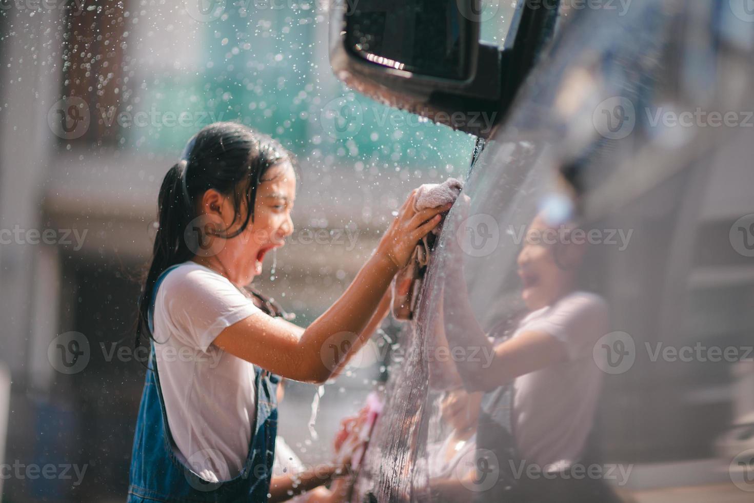 Sibling Asian girls wash their cars and have fun playing indoors on a hot summer day. photo