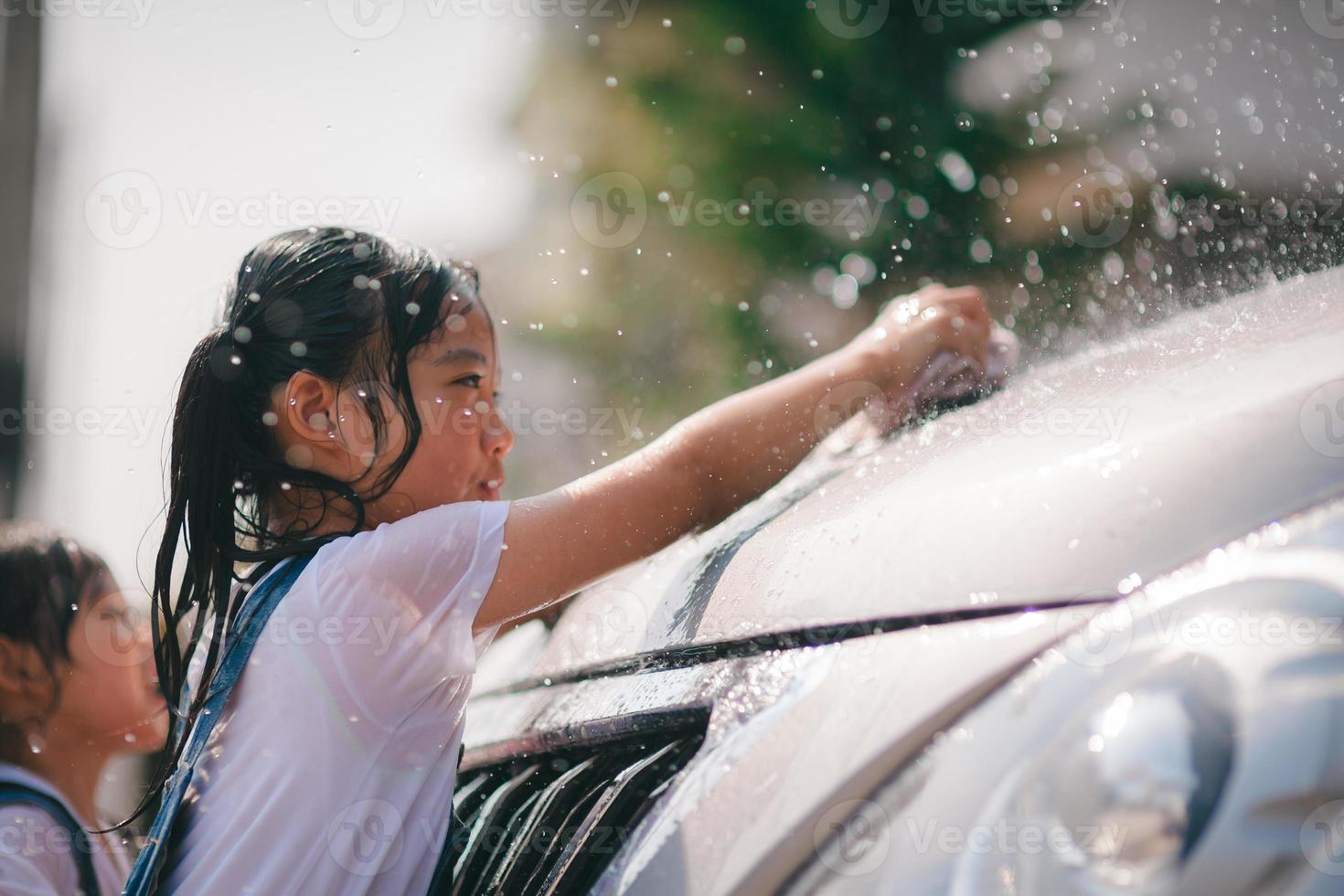 Sibling Asian girls wash their cars and have fun playing indoors on a hot summer day. photo