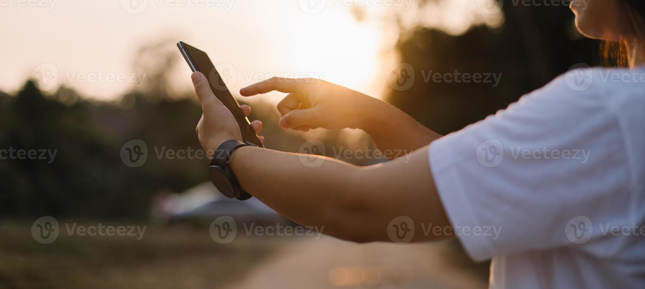 cerca arriba mujer mano sostener utilizando inteligente teléfono en al aire libre parque calle antecedentes. Copiar espacio de tecnología negocio y viaje fiesta concepto. Clásico tono filtrar efecto color estilo. foto