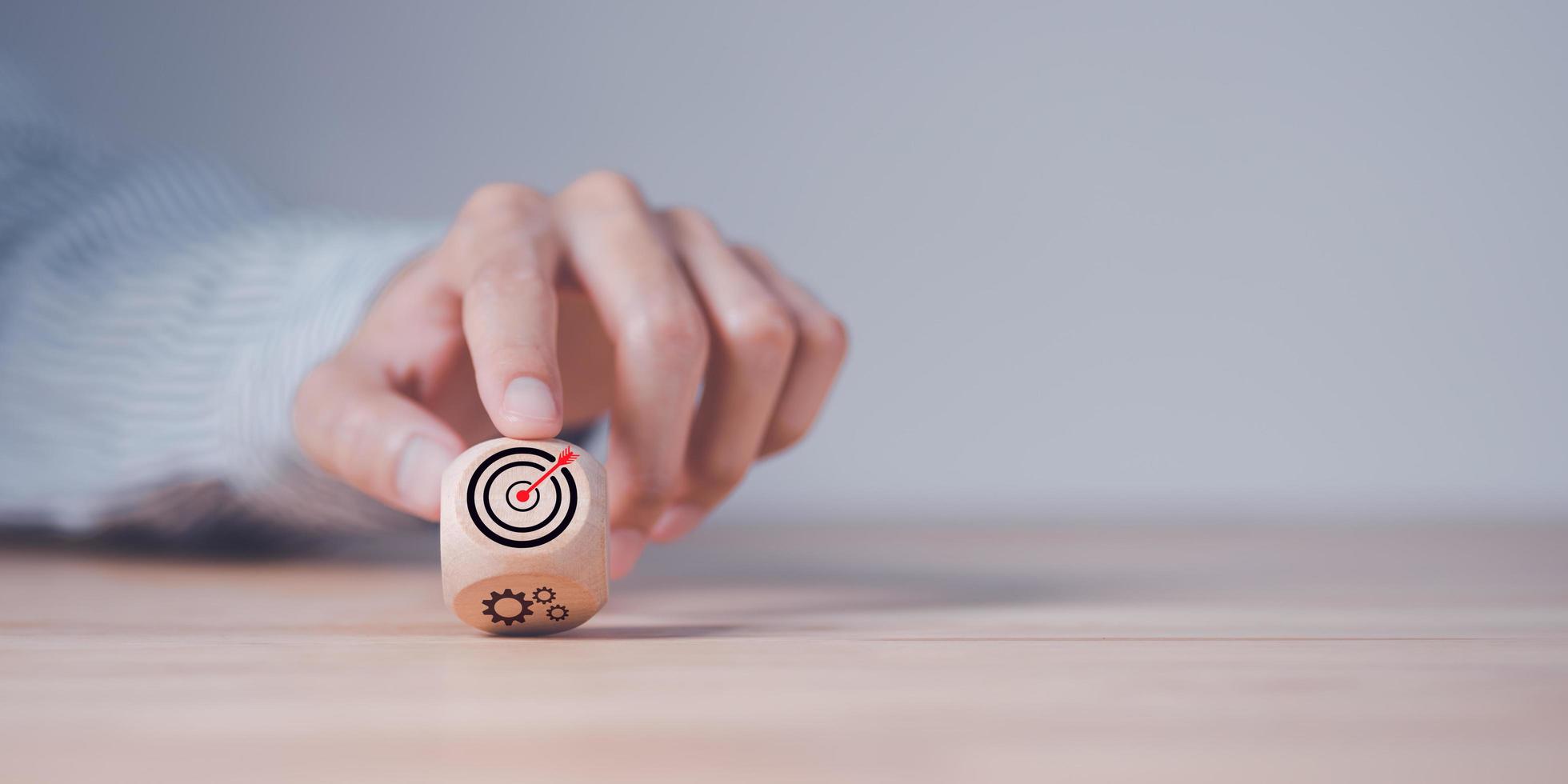 Wooden block in businessman hand and arrow icon hitting center of dartboard target,Setting business goals and focused concepts, Organizational growth and objectives, marketing strategy planning photo