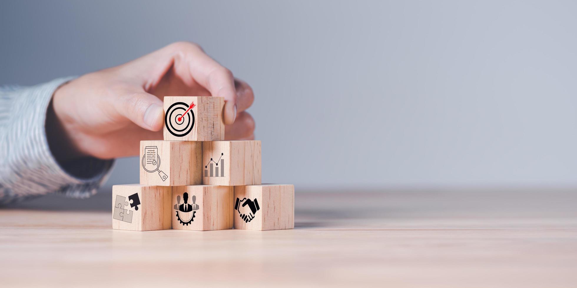 Wooden block in businessman hand and arrow icon hitting center of dartboard target,Setting business goals and focused concepts, Organizational growth and objectives, marketing strategy planning photo