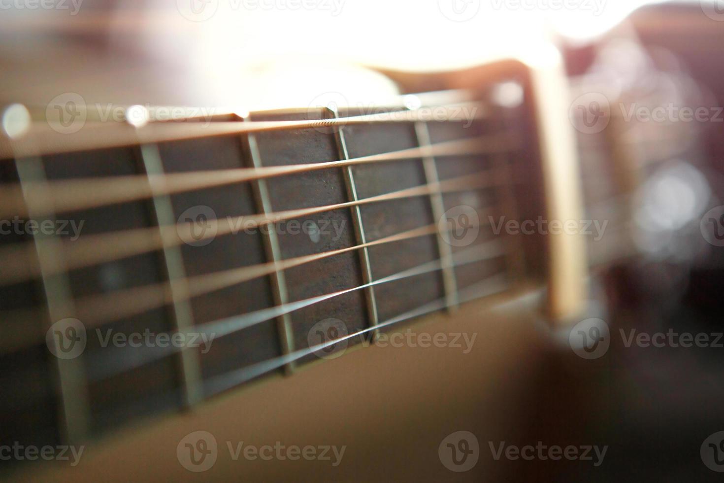 A man's hand on the fretboard of a guitar runs his fingers through the strings and clamps the chords. Instrumental music, guitar lesson on sheet music photo