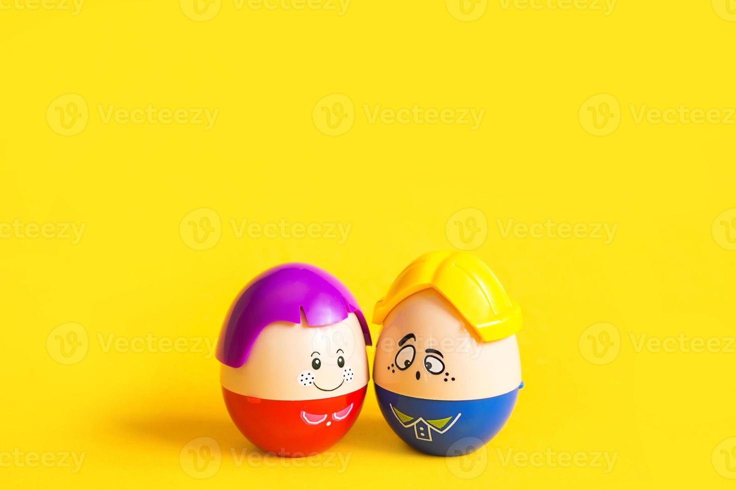 Two funny eggs boy and girl with faces on a yellow background - Easter, spring. Children's toys-a symbol of a couple of men and women, love, family. Copy space photo