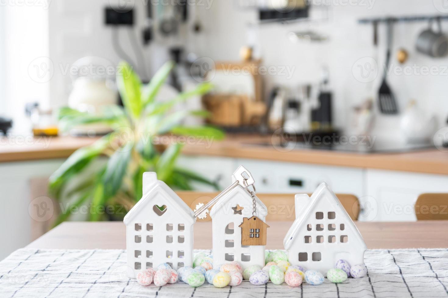 Key to house of cozy home with Easter decor with rabbit and eggs on table of kitchen. Building, design, project, moving to new house, mortgage, insurance, rent and purchase real estate photo